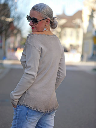 Frau in grauem Shirt trägt den OFF#DLY LS Mila taupe Strick-Longsleeve mit Rundhals und Spitzeneinsatz, kombiniert mit Sonnenbrille und Jeans; schmaler, gerader Schnitt, One Size bis Größe 40.
