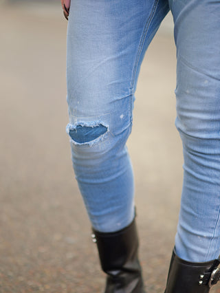 OFF#DLY Destroy Denim Isadora midblue, getragen von einer Person. Die Jeans hat einen zerrissenen Look, ist baggy geschnitten und zeigt schwarze Stiefel an den Füßen.
