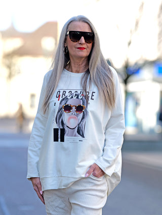 Frau trägt OFF#DLY Sweat obscure white mit funkelndem Frontprint und Sonnenbrille, gerade Passform. Ideal für lässige Anlässe.