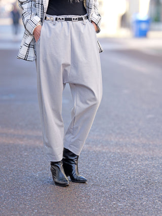 OFF#DLY Hose Zoe grau, getragen mit schwarzen Boots, zeigt eine Baggy-Passform mit feinen Bundfalten und seitlichen Taschen, aus 95% Baumwolle und 5% Elastan gefertigt.