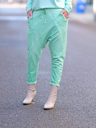 OFF#DLY Jogger Pant Tina türkis, getragen von einer Person, mit lässiger Baggy-Passform, Gummibund und Kordelzug. Sichtbare beige Stiefel und seitliche Taschen ergänzen den Look.