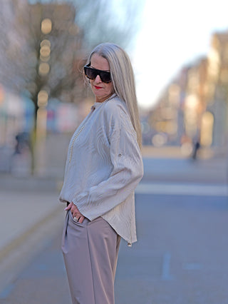 Die OFF#DLY Bluse Beate beige zeigt eine feine Schlupfbluse mit halber Knopfleiste und weiten Ärmeln, gefertigt aus 100% Viskose, in gerader Passform.