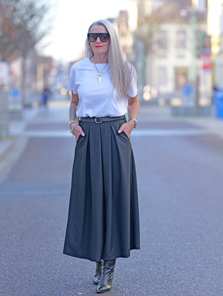 Frau trägt Liv Bergen Tee OKAY optic white mit Rundhalsausschnitt, kombiniert mit langer Rock, Sonnenbrille und schwarzen Stiefeln, im Straßenmode-Stil. Modelgröße: 172 cm, trägt Größe M.