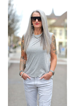 Liv Bergen Top EAST Melange, getragen von einer tätowierten Frau in einem grauen Tanktop, mit Rundhals und kleinen Patches. Perfekt für lässige Anlässe, aus Tencel und Baumwolle.