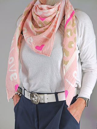 Frau trägt OFF#DLY Tuch LOVE rosa, ein großes Musselin-Dreieckstuch mit Print, kombiniert mit weißem Gürtel.