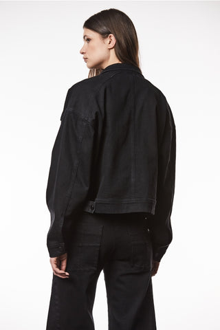 Thom Krom Jacke WJ 210 black: Frau trägt schwarze, taillierte, oversized Jeansjacke mit langen Ärmeln und Taschen, aus elastischem Denim-Stoff.