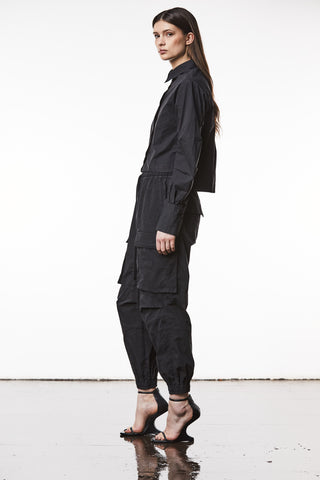 Thom Krom Bluse WH 16 black: Frau trägt schwarzes Baumwollhemd mit verdeckter Knopfleiste und Plissee-Details an den Ärmeln, kombiniert mit schwarzer Hose und schwarzen High Heels.