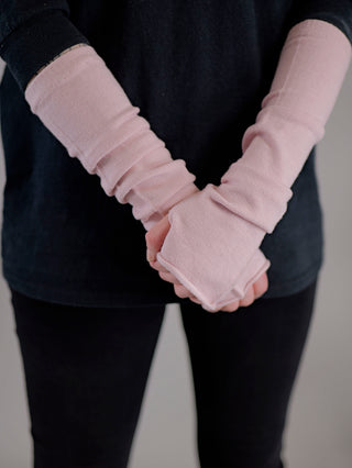 Eine Person trägt die OFF#DLY Stulpe rose mit pinken Handschuhen und hält ein Handtuch. Die Stulpe besteht aus Viskose, Nylon und Polyester, Größe One Size.
