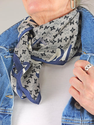 OFF#DLY Tuch Verona taupe zeigt eine Person, die ein feines Viskosetuch mit Allover-Print trägt, während ein silbernes Armband und ein Ring dezent im Bild erscheinen.