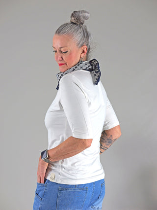 Frau trägt Cotton Candy Tee Bale white, ein langes, gerades T-Shirt mit Rundhals aus Viskose, kombiniert mit Jeans. Blick auf Tasche und Uhr am Arm.