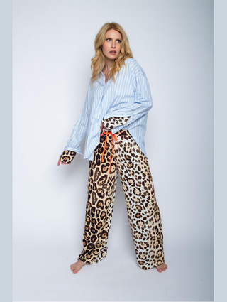 Frau trägt Emily Damenhose leo 8518-201410 mit weitem Bein und Leopardenmuster aus Viskose, kombiniert mit blauem Shirt. Hose hat elastisches Bündchen und seitliche Taschen.