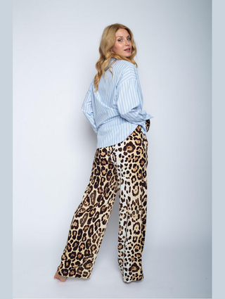 Emily Damenhose leo 8518-201410, getragen von einer Frau in blauer Bluse. Die Hose hat ein Leopardenmuster, weites Bein, elastisches Bündchen, und seitliche Eingriffstaschen, aus 100% Viskose gefertigt.