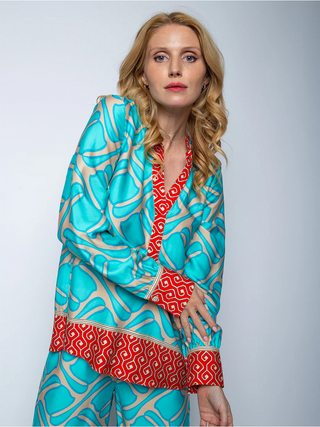Emily Bluse coral/border 8484-155950: Frau trägt eine elegante Bluse mit kleinem Kragen und V-Ausschnitt, langen Ärmeln mit Manschetten, zweifarbigem Druck und Kontrastbordüre aus Viskose Satin.