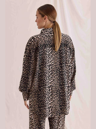 Rückansicht einer Frau in einer oversized Cotton Candy Bluse Zoe multicolor mit Leoprint und Knopfleiste, die einen lässigen Look ausstrahlt.