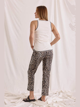 Frau trägt das Cotton Candy Top Roca offwhite, ein enges, geripptes Tanktop mit weitem Rundhals und Logostick, kombiniert mit Leopardenmuster-Hose und schwarzen Sandalen.