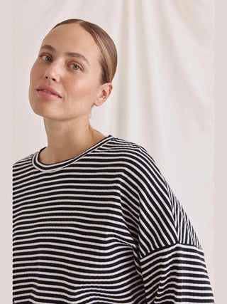 Frau in gestreiftem Cotton Candy Tee Fjolla, lässiges, geripptes Langarmshirt in Oversized-Passform. Fokus auf Streifenmuster und angenehmem Tragekomfort durch hochwertige Materialzusammensetzung.
