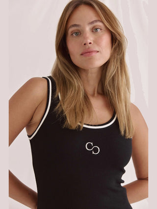 Miranda-Kleid in Schwarz von Cotton Candy: Enganliegendes, geripptes Design mit weitem Rundhals und Logostickerei, getragen von einer Frau mit langem, blondem Haar im Fotoshooting-Stil.