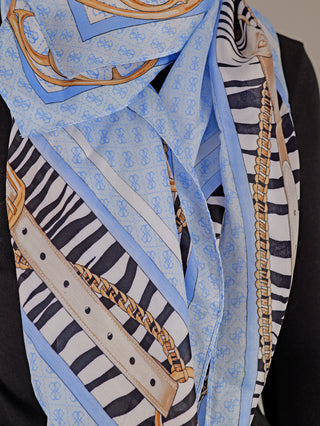 Guess Zamira Foulard LBU: quadratischer Schal auf einer Schaufensterpuppe, mit auffälligem Animalprint, Gürtel- und 4G-Logo-Muster, aus 100% Viskose, drapiert für modische Präsentation. Maße 130 x 130 cm.