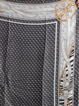 Nahaufnahme des Guess Zamira Foulard CLO mit Animalprint, Gürteldetails und 4G-Logo auf einem quadratischen, 130 x 130 cm großen Tuch aus 100 % Viskose.