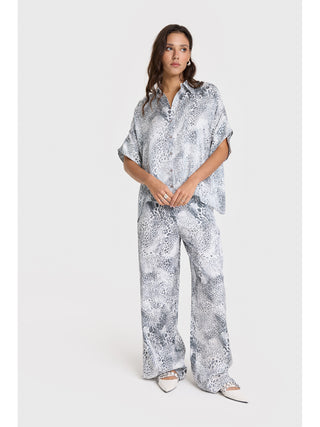 ALIX ANIMAL Bluse: Frau trägt eine übergroße Bluse mit Allover-Tierprint aus glänzendem Viskosegewebe, ergänzt durch ALIX-Logo-Bänder auf der Rückseite. Perfekt für modische Akzente.