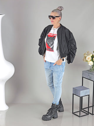Frau trägt das OFF#DLY Tee Ready white mit Katzenprint und Strassteinen, kombiniert mit blauer Jeans.