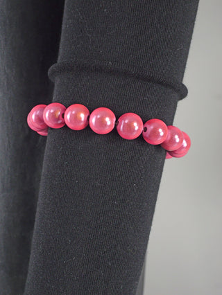 OFF#DLY Kugelarmband 9 mm rosa Magic, ein modisches Armband aus pinkfarbenen Acrylperlen, liegt auf schwarzer Oberfläche. Elegantes Design, perfekt als Accessoire.