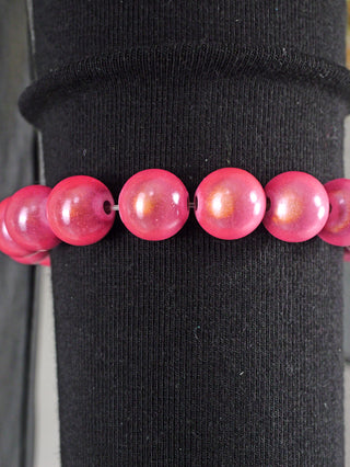 OFF#DLY Kugelarmband 9 mm rosa Magic: Ein Armband aus rosa Acrylperlen auf schwarzem Hintergrund, zeigt glänzende, runde Details im Nahbereich.