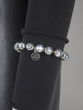 OFF#DLY Kugelarmband 10 mm silber, ein hochglanzbeschichtetes Aluminiumarmband, präsentiert auf einem Ärmel. Sichtbar sind glänzende Silberkugeln, die das moderne und elegante Design betonen.
