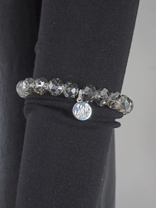 OFF#DLY Glasperlenarmband grau, ein modisches Accessoire aus Glasperlen mit silbernen Akzenten, präsentiert auf dunklem Stoff. Exquisites Design mit funkelnden Elementen verleiht eleganten Glanz.