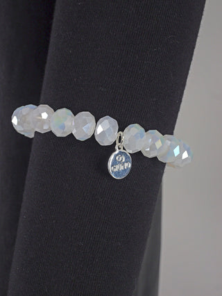 OFF#DLY Glasperlenarmband weiß matt auf schwarzer Oberfläche, zeigt silberne Details und einen Kristallanhänger, mit Glasperlen von etwa 9 mm Durchmesser, in Freigröße.