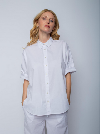 Emily Bluse 4890-154971 white: Frau trägt weiße, lockere Hemdbluse mit modernem Halbarm und Knopfleiste, passend zu weißen Hosen, aus softer Baumwoll-Elastan-Mischung, ideale Oversize-Passform.