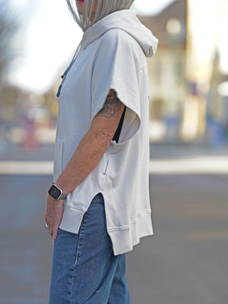 Person trägt Nuomeno Hoody 14164 tofu mit Kapuze und Rückenprint. Der ärmellose Sweater hat eine oversized Passform und ist aus 100% Baumwolle. Model trägt Größe S.