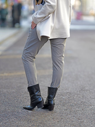 OFF#DLY Joggpant Leila taupe, getragen von einer Frau mit grauen Hosen und schwarzen Boots, schmal geschnitten mit Doppeltaschen vorne, Kordelzug und Gummibund, passend für Größen 34 bis 42.
