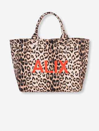 ALIX Leo Shopper Tasche mit auffälligem Leopardenmuster und rotem „ALIX“-Schriftzug, gefertigt aus schwerem Canvas-Stoff. Die Tasche verfügt über einen Magnetknopfverschluss und ein Reißverschlussfach innen.