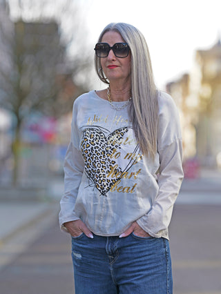 OFF#DLY Longsleeve Wild Heart white/gold: Frau mit grauen Haaren trägt ein weißes Shirt mit Herzmotiv, Lurex-Nähte am Kragen, Hände in den Taschen, Sonnenbrille als Accessoire.