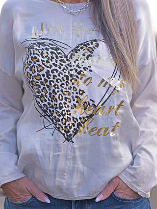 Person trägt das OFF#DLY Longsleeve Wild Heart white/gold mit Herz- und Leopardenprint. Der Stoffmix und die Lurex-Nähte am Kragen und Bund sind erkennbar.