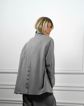 Gitta Banko Blazer Alison grey, getragen von einer Frau, zeigt einen zweireihigen Schnitt mit auffälliger Knopfleiste und seitlichen Taschen. Der Blazer hat eine oversized Passform.