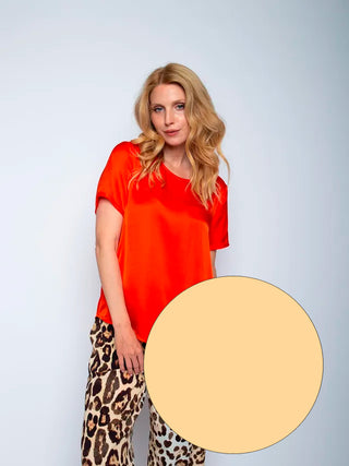 Emily Bluse sand 156100: Frau trägt ein rotes Rundhals-Shirt mit modernem Halbarm und offenen Kantenblenden. Gerade Passform aus Viskose Satin, passend für Konfektionsgröße 36, getragen von Model.