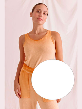 Frau in einem weißen Cotton Candy Top Aurelia, ärmellos mit besonderem Saum, posiert. Das Top hat einen körperbetonten Schnitt und bietet hohen Tragekomfort.