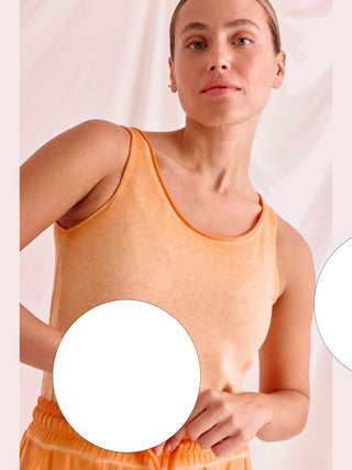 Frau trägt das Cotton Candy Top Aurelia white, ein körperbetontes Tanktop mit besonderem Saum, das aufgrund seiner Materialzusammensetzung für hohen Tragekomfort sorgt.