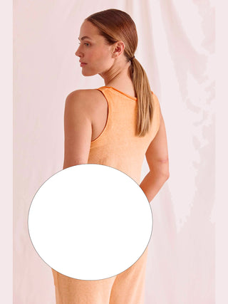 Eine Frau trägt das Cotton Candy Top Aurelia white, ein figurbetontes, ärmelloses Oberteil mit besonderem Saum und angenehmem Tragekomfort, modelliert von einer Frau in einem orangefarbenen Tanktop.