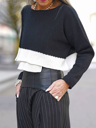 Frau trägt den Rundholz Pulli 3720703 im schwarzen Print, mit lässiger Passform und auffälligem Design. Hand in der Tasche unterstreicht die entspannte Eleganz des Looks.