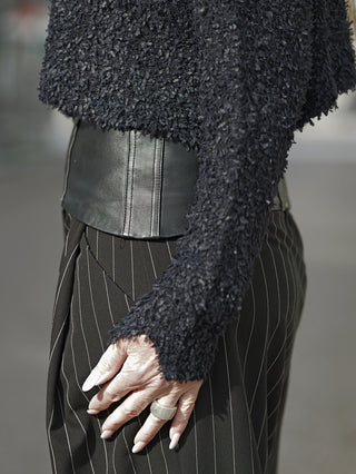 Person trägt den Rundholz Pulli 3480703 black mit avantgardistischem Design, feinen All-over-Fransen, großzügigem Rundhalsausschnitt und langen Ärmeln, passend für eine moderne, lässige Silhouette.