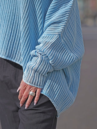 Eine Person trägt den Rundholz Strick 3450701 malibu cloud Pullover mit einem sportlichen Netzdesign und einer lockeren, oversized Passform, während ihre Hand einen Ring präsentiert.