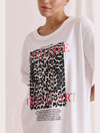 Frau trägt das Cotton Candy Tee Umut white Print mit Leopardenmuster, lockerem Schnitt und Rundhalsausschnitt, ideal für lässigen Stil.