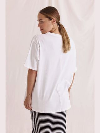 Frau in weißem Cotton Candy Tee Umut mit Aufdruck, lässig geschnitten, Rundhalsausschnitt, Oversize-Passform, sichtbar sind Schulter- und Haarpartie.