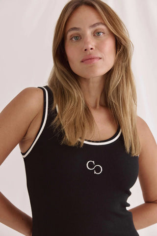 Frau trägt das Cotton Candy Top Roca black, ein enges, geripptes schwarzes Tanktop mit weitem Rundhals, Kontrastdetails und Logostick, ideal für komfortablen, körpernahen Sitz.