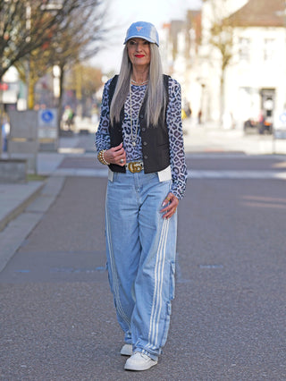 Frau in Leopardenhemd und blauer Jeans trägt die OFF#DLY Weste Sonja black, eine elegante schwarze Anzugweste mit schlanker Passform und Knopfverschluss, perfekt für modische Outfits.