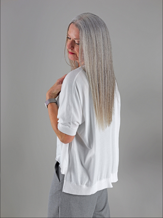 Frau trägt ein Cotton Candy T-Shirt Helay weiß mit V-Ausschnitt und gerippten Ärmelabschlüssen, locker sitzend. Das Shirt ist oversized und angenehm zu tragen.