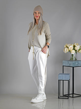 Eine Frau trägt die OFF#DLY Hose Mirella in Offwhite, eine sportliche Joggpant mit Gummibund und Kordelzug, seitlichen Einschubtaschen und geradem Schnitt.